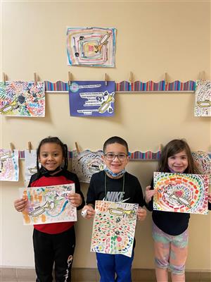 Photo shows three students holding art painted in the style of Alma Woodsey Thomas.